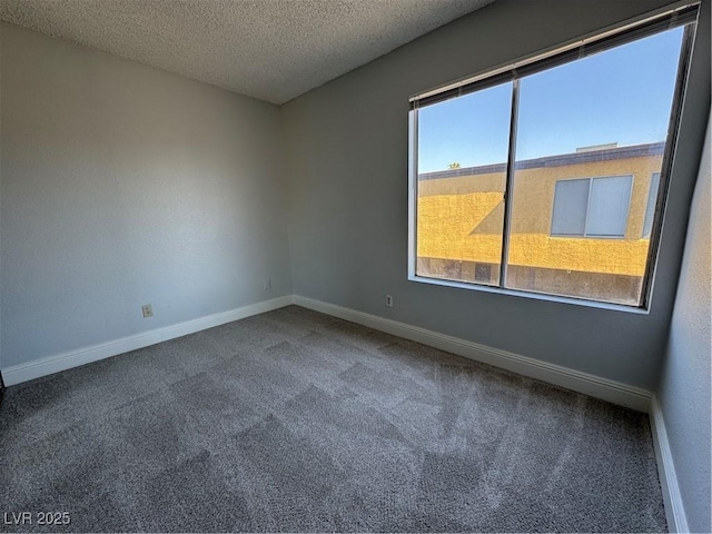 unfurnished room featuring a textured ceiling, carpet, and baseboards