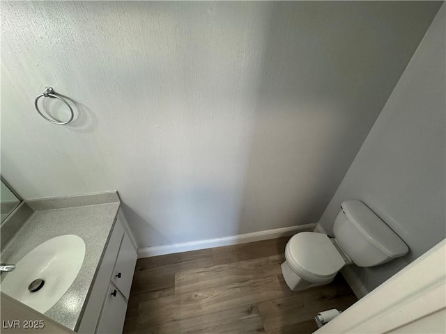 bathroom with wood finished floors, vanity, toilet, and baseboards