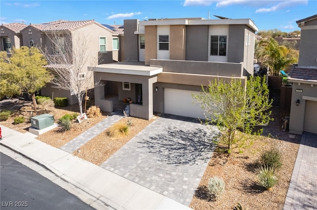 view of front of home featuring a garage, decorative driveway, a tile roof, and stucco siding