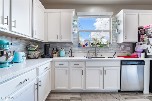 kitchen with light countertops, white cabinets, dishwasher, and a sink