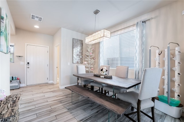 dining room with wood finish floors, visible vents, a notable chandelier, and baseboards