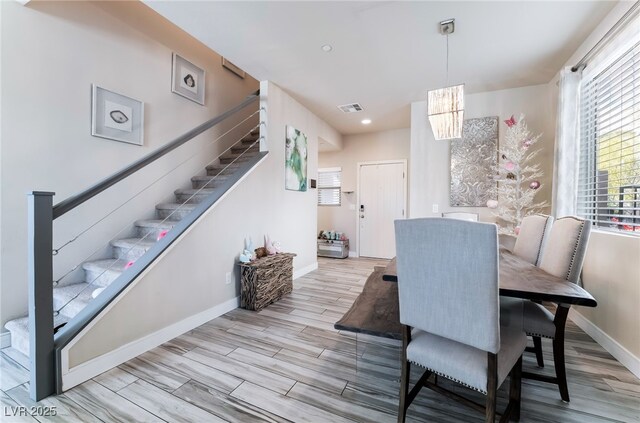 dining space with baseboards, visible vents, stairway, wood finished floors, and a chandelier