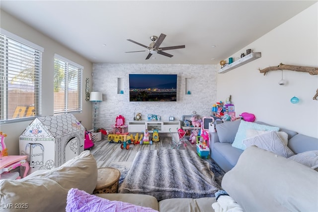 living area with an accent wall and a ceiling fan