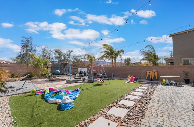 view of jungle gym featuring a patio area, a fenced backyard, a trampoline, and a lawn