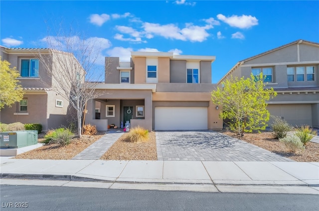 view of front facade featuring decorative driveway, an attached garage, and stucco siding