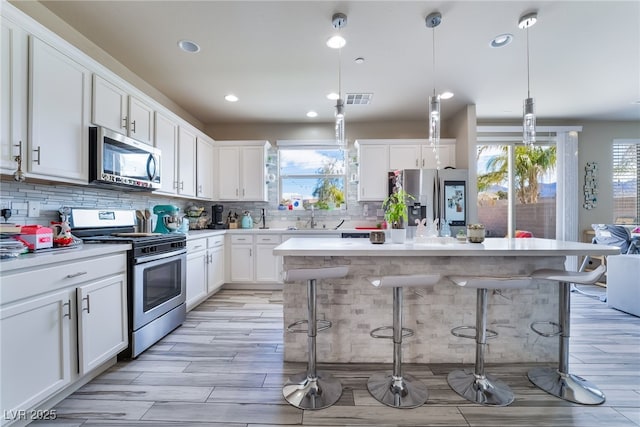 kitchen with a breakfast bar area, a sink, visible vents, appliances with stainless steel finishes, and backsplash