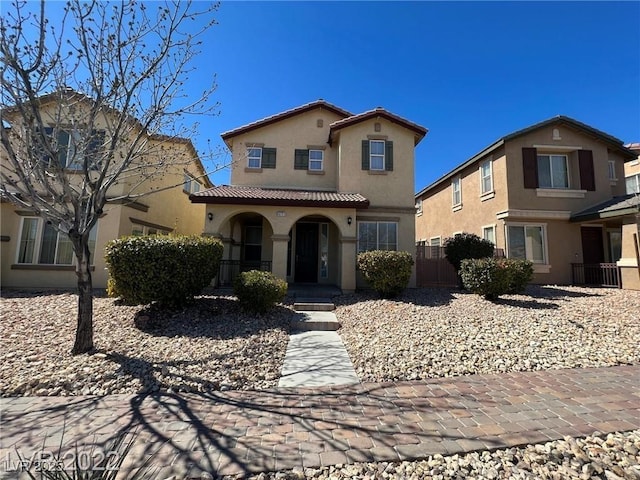 mediterranean / spanish-style home with a tile roof, fence, a porch, and stucco siding