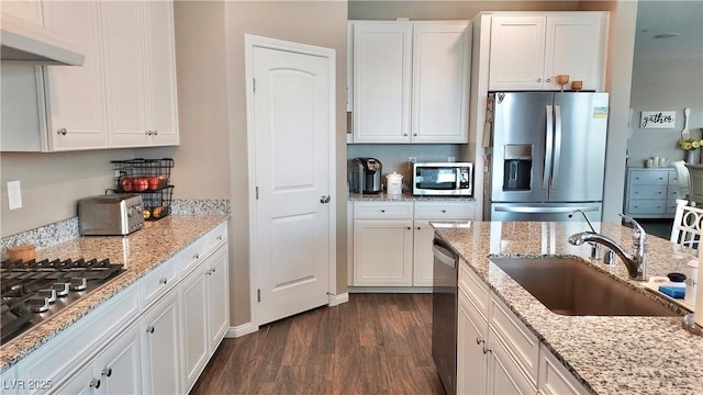 kitchen featuring appliances with stainless steel finishes, dark wood-type flooring, white cabinets, a sink, and under cabinet range hood