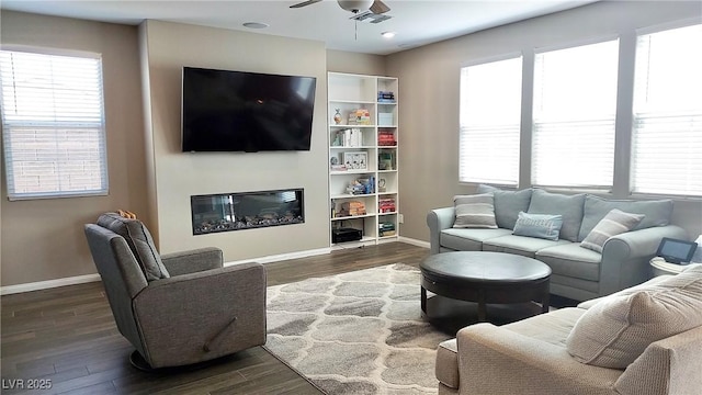 living area featuring a glass covered fireplace, baseboards, and wood finished floors