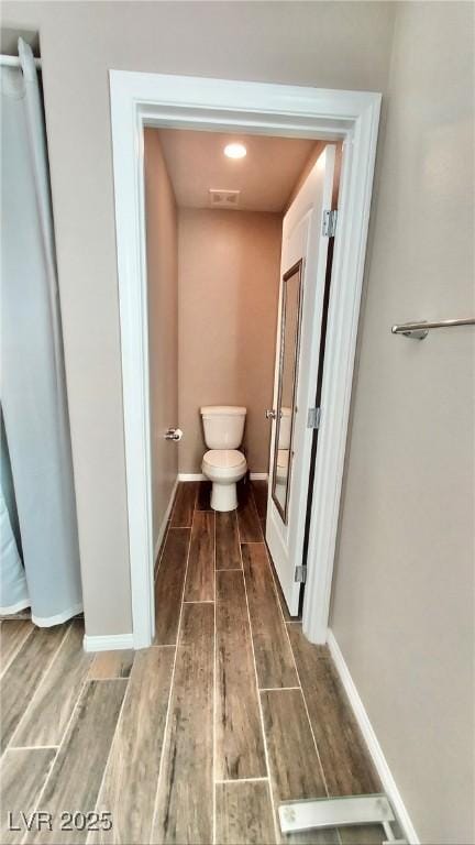 bathroom featuring toilet, baseboards, and wood finished floors