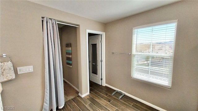 hallway featuring wood finish floors and baseboards