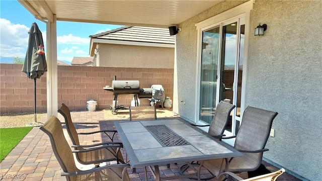 view of patio featuring outdoor dining space, a grill, and fence