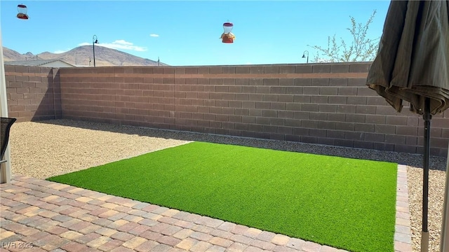 view of yard with a fenced backyard and a mountain view