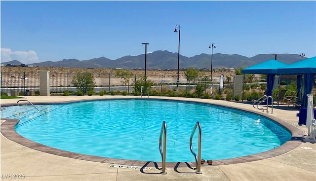 community pool featuring a patio area, fence, and a mountain view