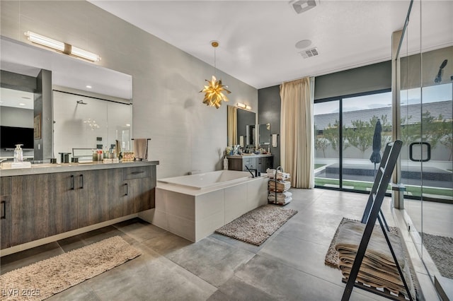 bathroom with a stall shower, visible vents, a garden tub, concrete flooring, and vanity