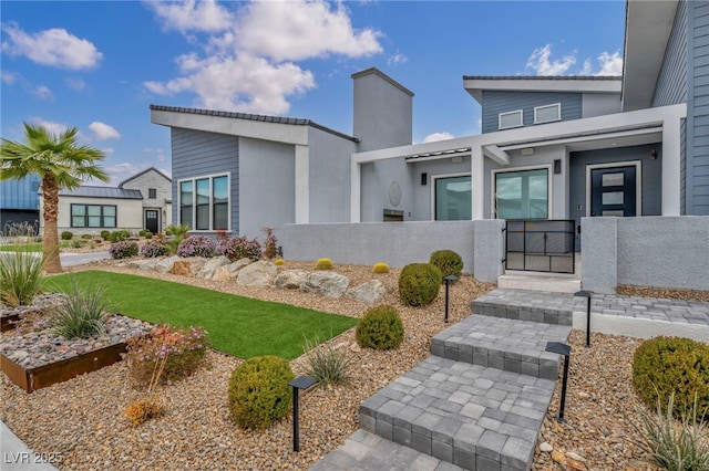 entrance to property featuring a gate, fence, and stucco siding