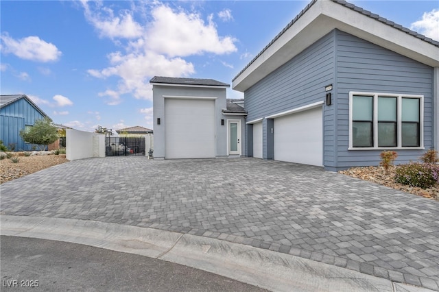 view of side of property with decorative driveway and an attached garage