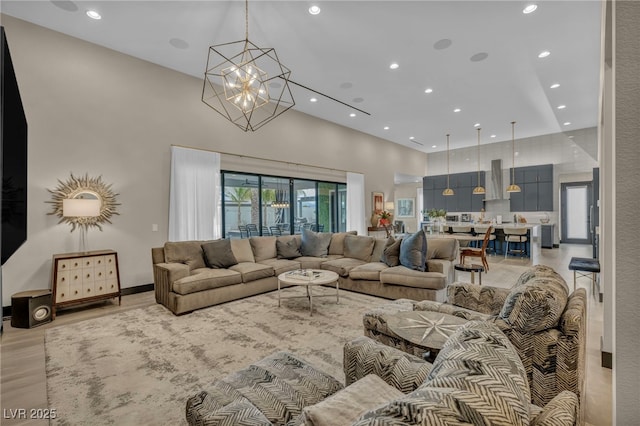 living area featuring a high ceiling, light wood-type flooring, an inviting chandelier, and recessed lighting