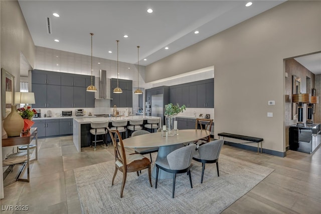 dining space featuring recessed lighting, a towering ceiling, and baseboards