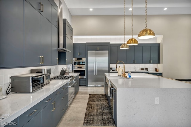 kitchen featuring a toaster, a center island with sink, hanging light fixtures, decorative backsplash, and high quality appliances