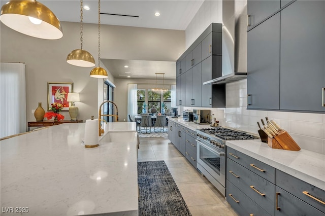 kitchen featuring a sink, high end stainless steel range oven, gray cabinets, backsplash, and wall chimney exhaust hood