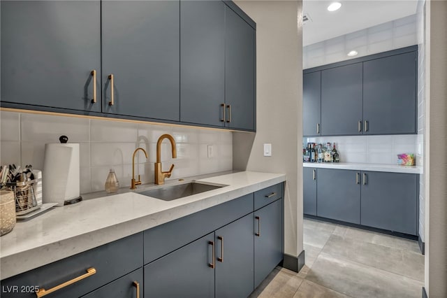 kitchen with blue cabinetry, decorative backsplash, a sink, and light countertops