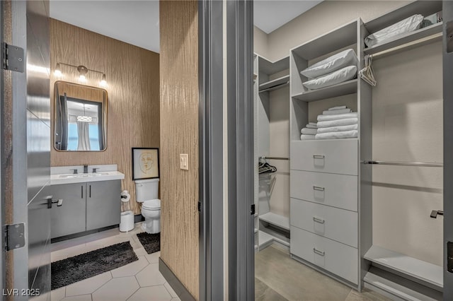 bathroom with a spacious closet, tile patterned flooring, vanity, and toilet