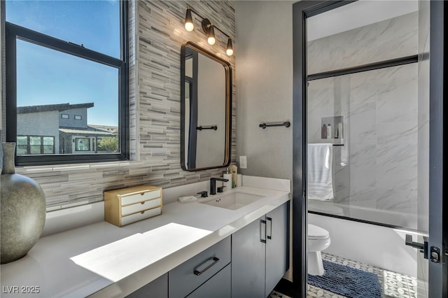 bathroom with combined bath / shower with glass door, backsplash, vanity, and toilet