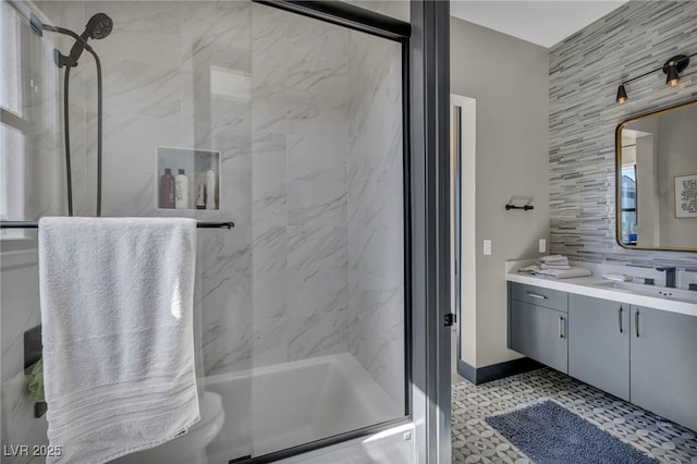 bathroom featuring tasteful backsplash, vanity, baseboards, and bath / shower combo with glass door