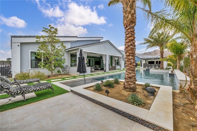 back of property with an outdoor pool, a patio area, fence, and stucco siding