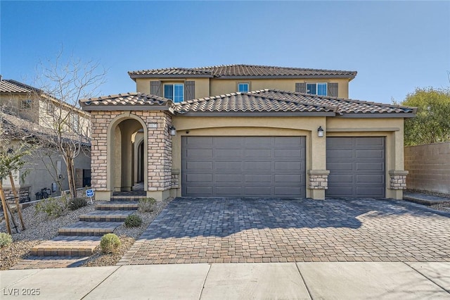 mediterranean / spanish-style house featuring stone siding, decorative driveway, an attached garage, and stucco siding