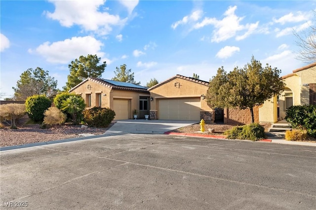 mediterranean / spanish-style home featuring concrete driveway, an attached garage, roof mounted solar panels, and stucco siding