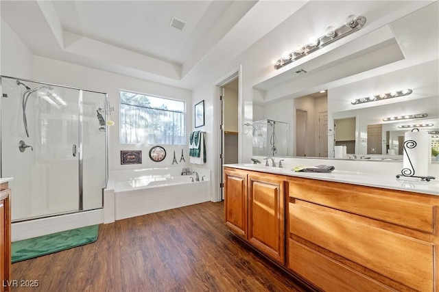 bathroom featuring a tray ceiling, visible vents, a stall shower, wood finished floors, and a bath