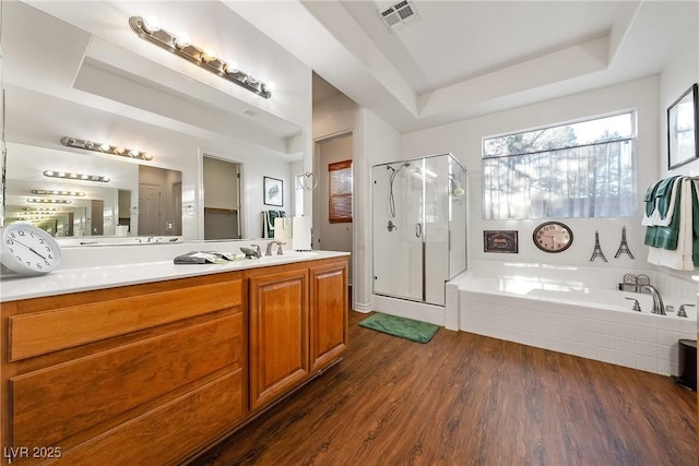 bathroom with a garden tub, wood finished floors, visible vents, a shower stall, and a tray ceiling