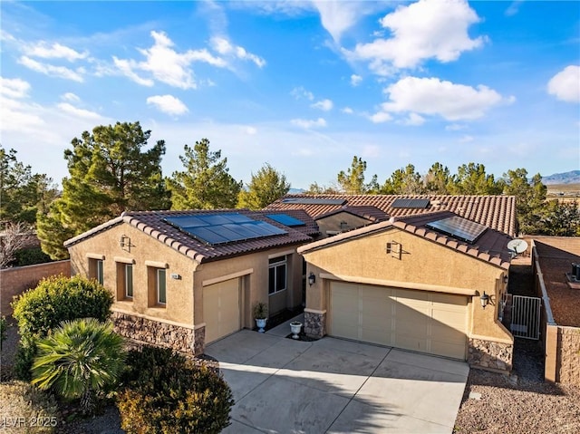 mediterranean / spanish-style home with an attached garage, stone siding, solar panels, and stucco siding