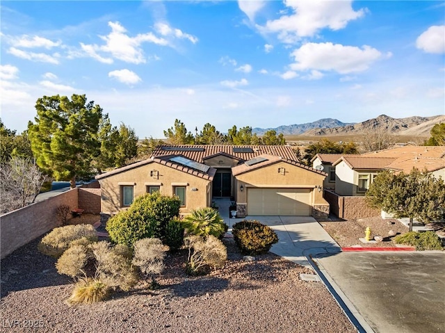 view of front of property with a garage, concrete driveway, fence, a mountain view, and stucco siding