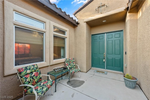 entrance to property featuring a tile roof and stucco siding