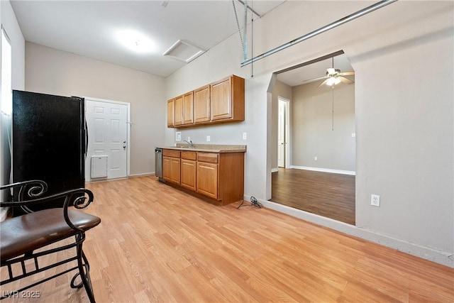 kitchen with light wood-style floors, baseboards, stainless steel dishwasher, and freestanding refrigerator