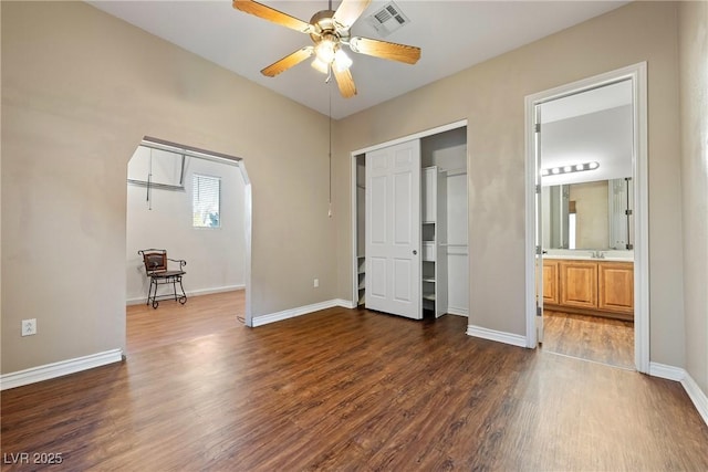 unfurnished bedroom with a closet, dark wood-style flooring, visible vents, and baseboards