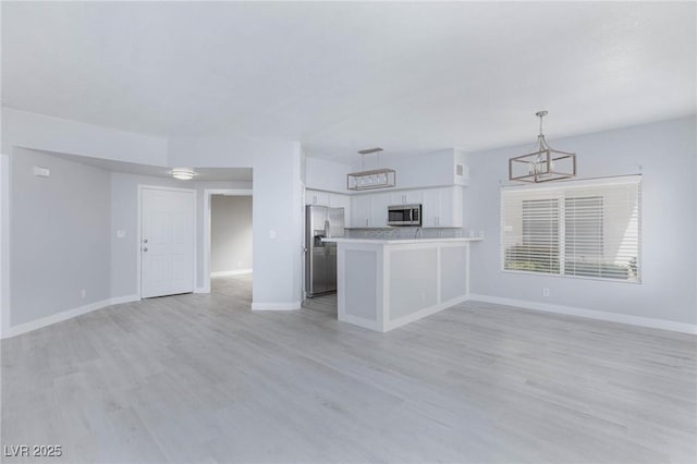 kitchen with white cabinets, appliances with stainless steel finishes, open floor plan, and light countertops