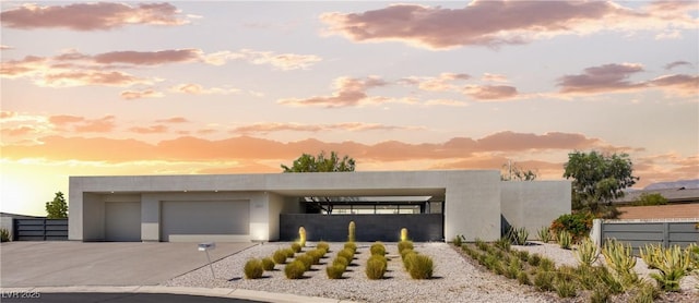 view of front of house featuring driveway, fence, and stucco siding