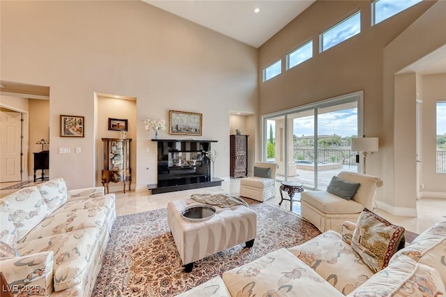 living area with light tile patterned floors, a glass covered fireplace, and baseboards