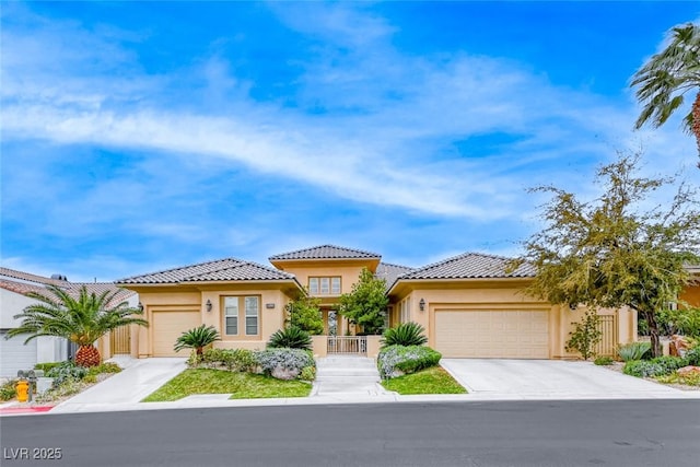 mediterranean / spanish home with a garage, concrete driveway, a tiled roof, and stucco siding