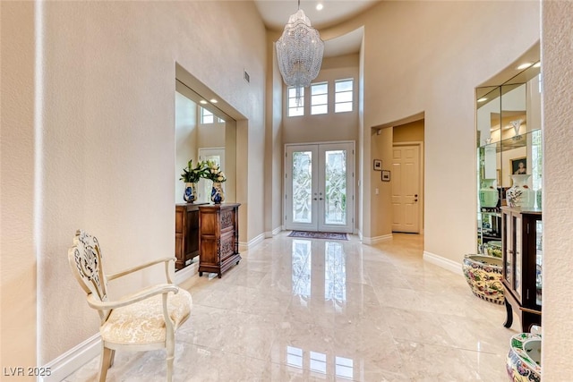 foyer entrance with a notable chandelier, french doors, a high ceiling, and baseboards