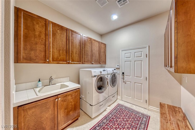 clothes washing area with washing machine and clothes dryer, cabinet space, a sink, and visible vents