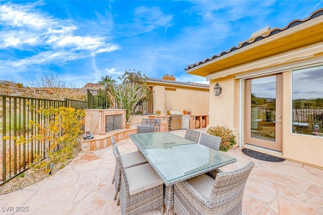 view of patio / terrace featuring outdoor dining area, an outdoor kitchen, fence, and a grill