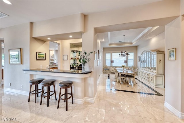 kitchen featuring a chandelier, recessed lighting, a raised ceiling, and baseboards