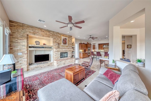 living room with recessed lighting, visible vents, a ceiling fan, and a stone fireplace