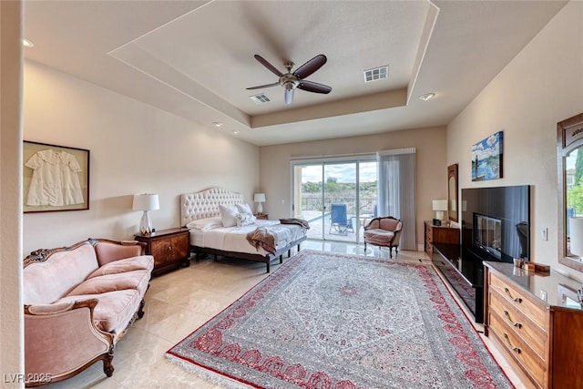 bedroom featuring a raised ceiling, visible vents, a glass covered fireplace, light tile patterned flooring, and access to outside