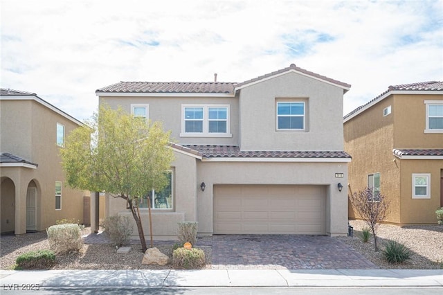 view of front facade with a tiled roof, decorative driveway, an attached garage, and stucco siding